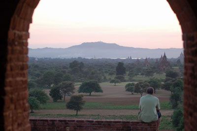 A tourist enjoying views of Tent Kyi hill, Ayeyarwaddy river and stupas from Pyatthad Gyi Pagoda, Bagan