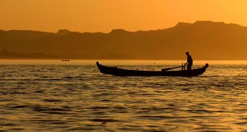 A hand paddled boat crossing the wide waters of Ayeyarwaddy river
