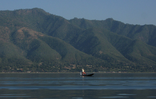 Fisherman rowing the boat with one leg